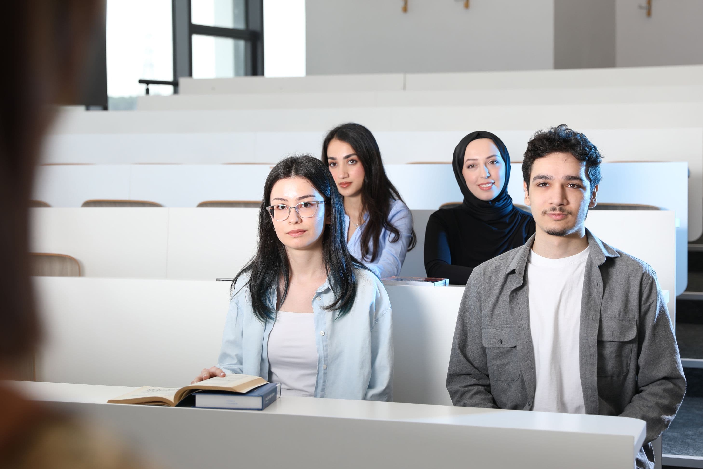 Student looking for help to take my exam while balancing work and studies with books and laptop